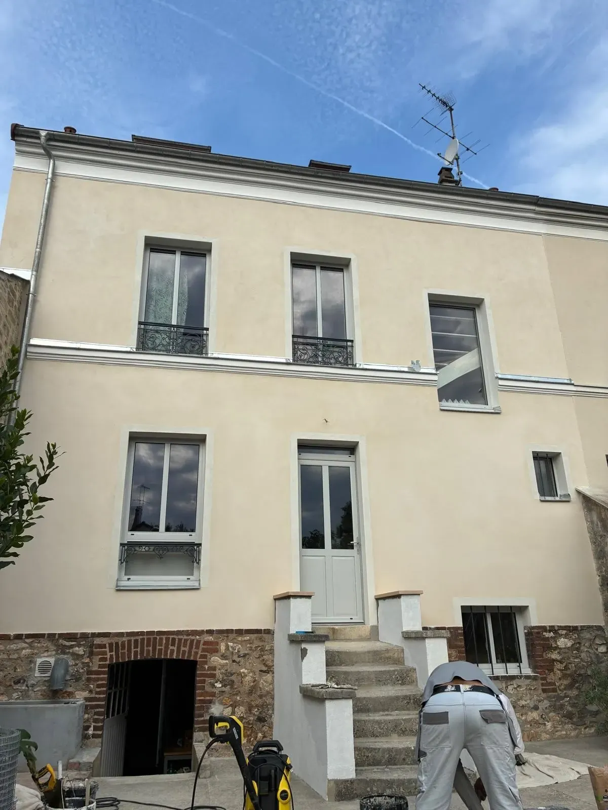 Façade de la maison de ville après ravalement : enduit crème, fenêtres neuves et soubassement en brique, 2 rue Séverine à Houilles
