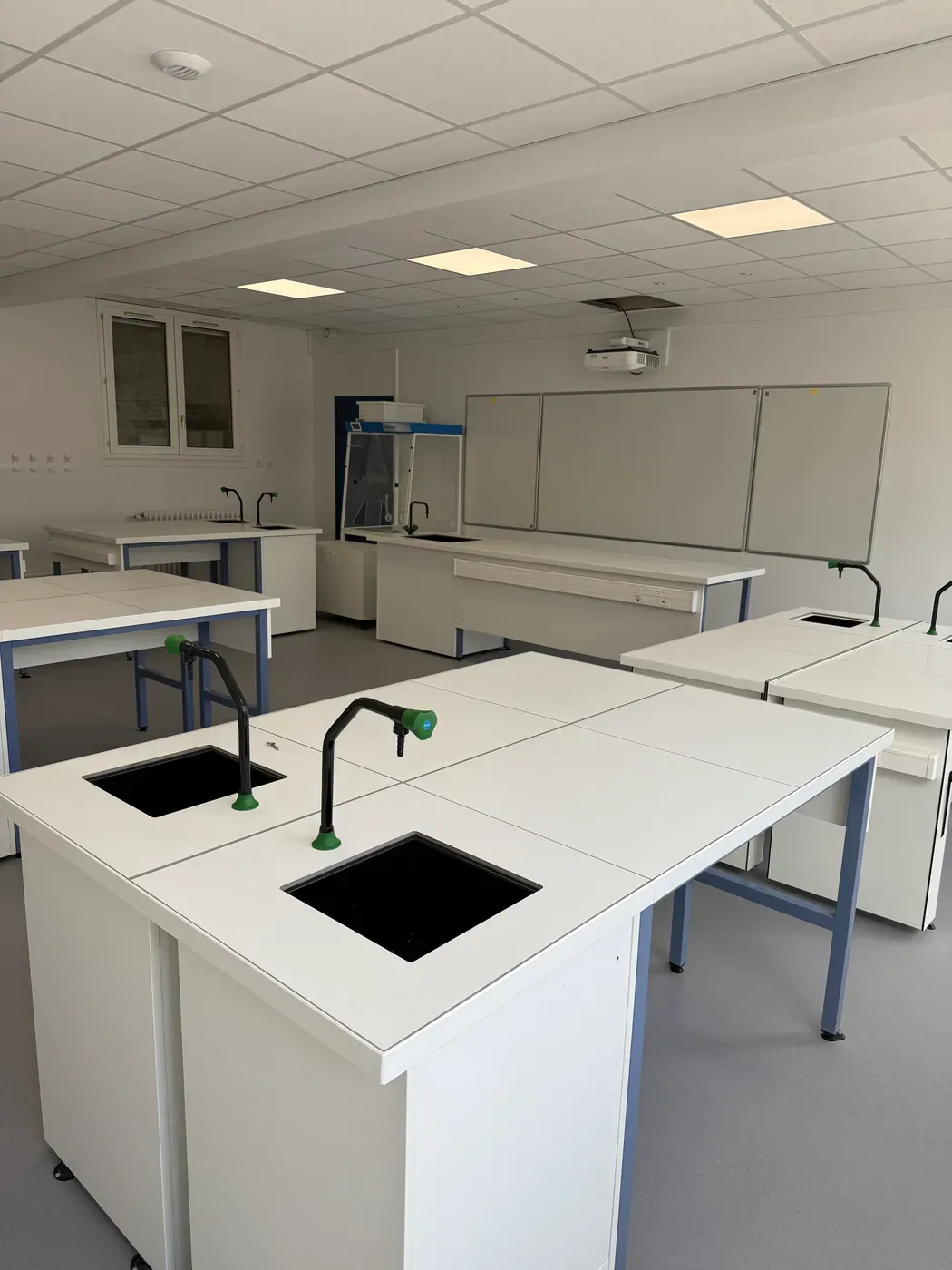 Salle de laboratoire équipée après travaux, paillasses alignées sous un éclairage LED